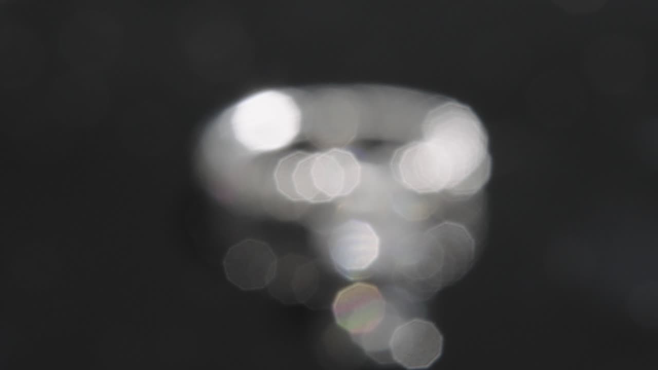 Close up, out of focus diamond ring rotating, black studio background