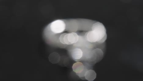 close up, out of focus diamond ring rotating, black studio background