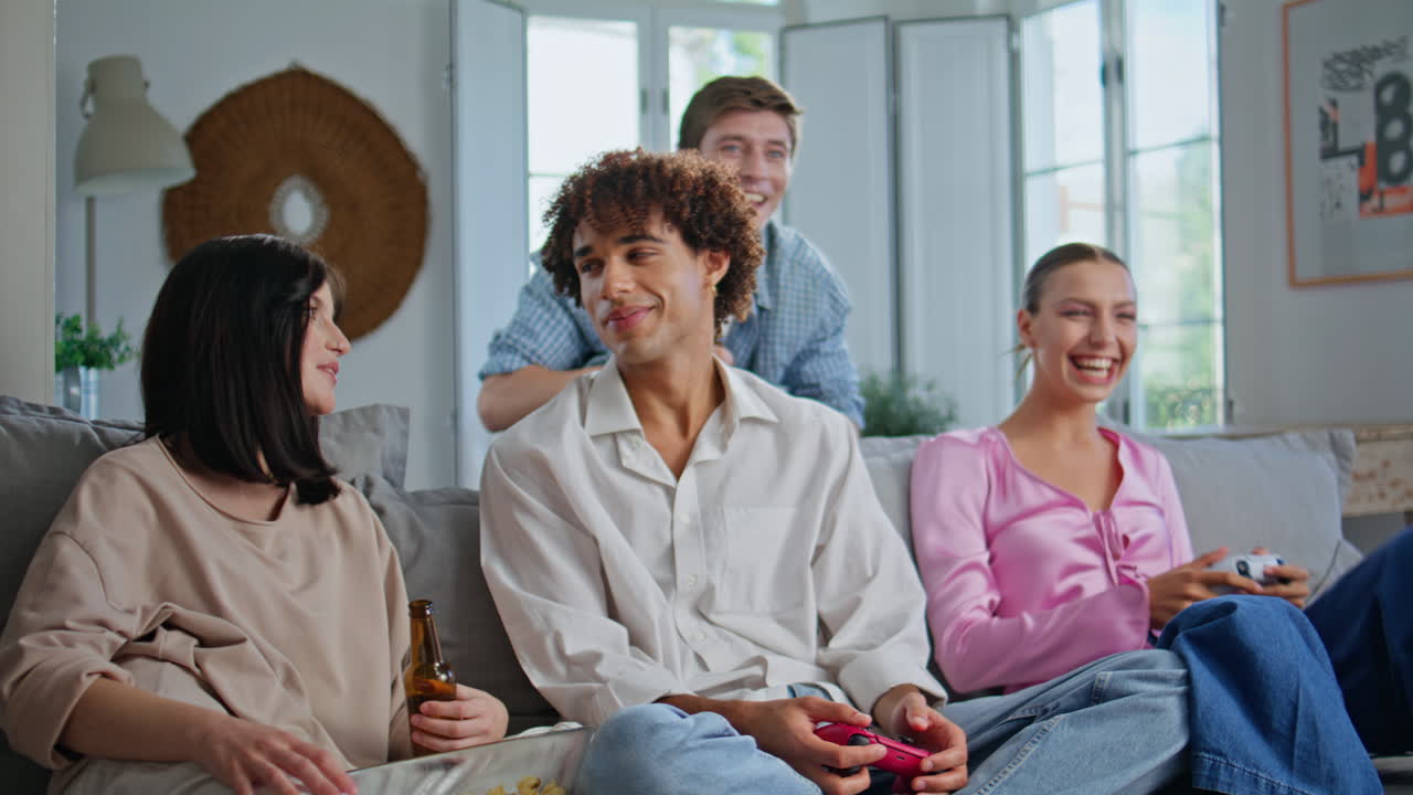 Emotional friends enjoying videogame on home couch with happy buddies closeup