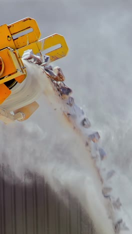 a powerful machine releases a blast of debris into the air, showing intense force during a cleanup operation - vertical shot