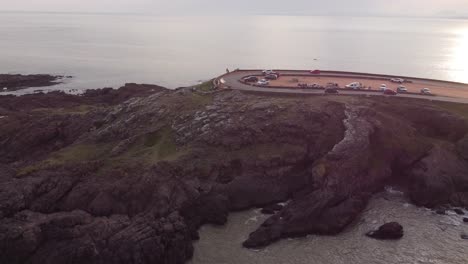 Aerial-orbit-shot-of-cars-parking-at-mountain-top-with-ocean-view-during-sunset-time---Punta-del-Este-Beach,Uruguay