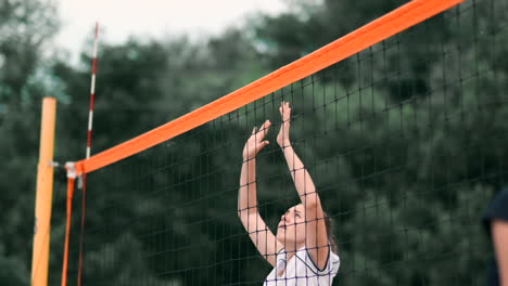 Young-woman-playing-volleyball-on-the-beach-in-a-team-carrying-out-an-attack-hitting-the-ball.-Girl-in-slow-motion-hits-the-ball-and-carry-out-an-attack-through-the-net.