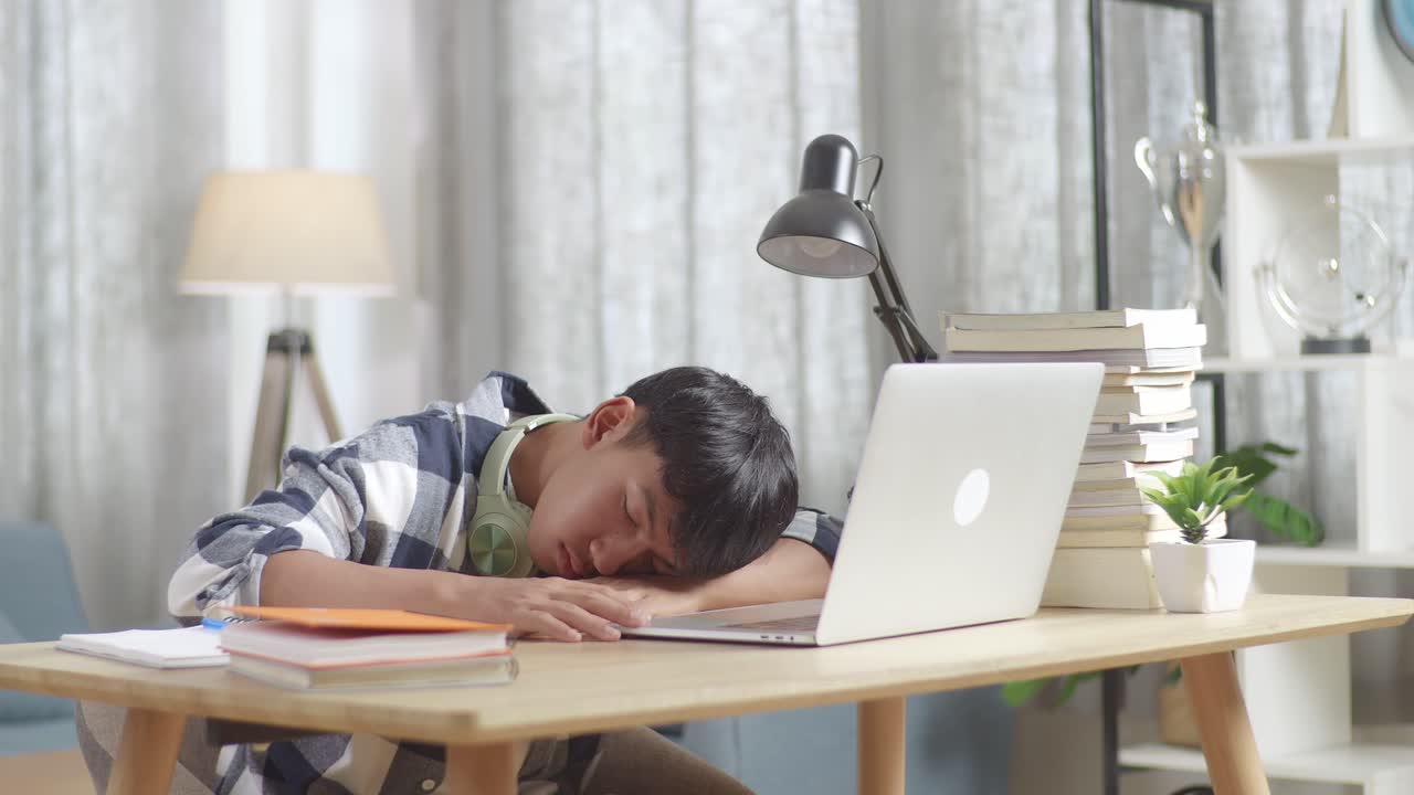온라인 숙제를 하는 동안 책상에서 자고 있는 십대