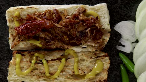 A-wide-shot-of-a-mini-Ciabatta-loaf-covered-in-mustard-and-ripped-chicken-topped-with-sun-dried-tomatoes