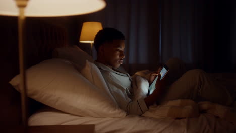 young person using tablet in bed at night