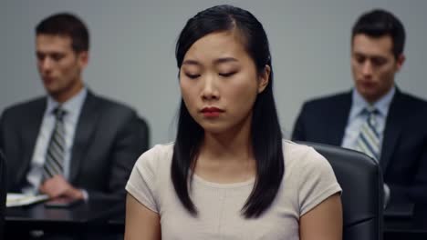 a woman is yawning with a look of boredom during a corporate meeting. in the background, two men in suits observe the proceedings intently, highlighting the contrast in engagement levels.