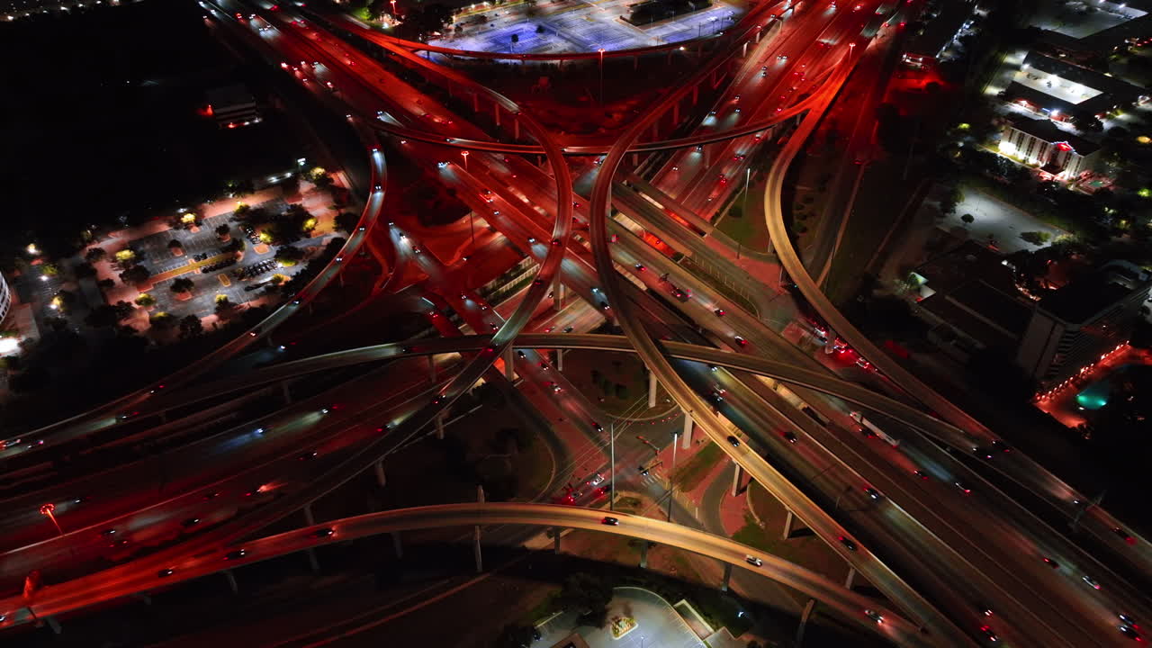 Stunning scenery of multi-level road interchange illuminated red. Lively traffic on the highways of a metropolis from drone footage
