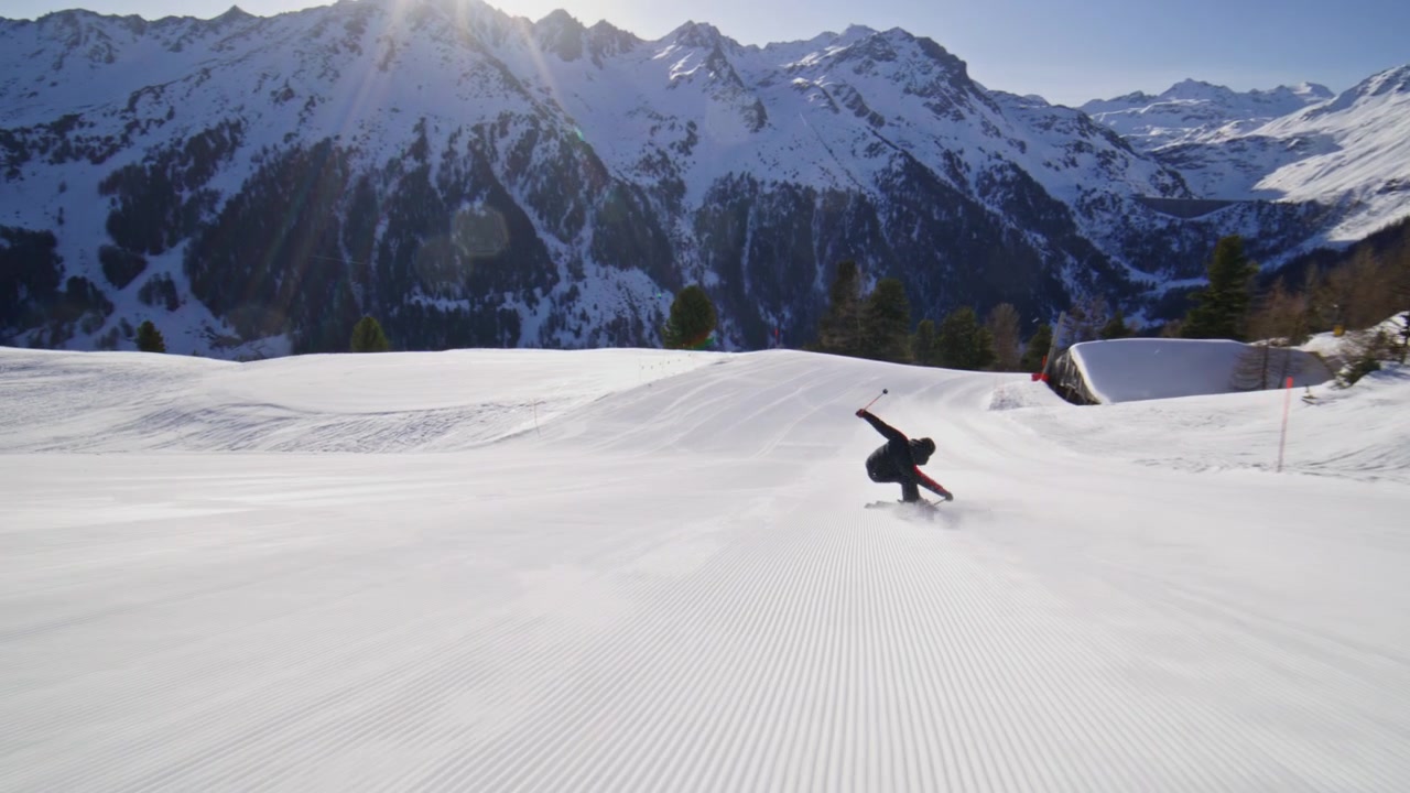 Skier carving groomed pistes at high speed in Nendaz, part of the 4 Vallées ski area in the Swiss Alps. Elite alpine skiing with powerful snow spray and precision technique.