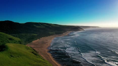 aerial view hilly green coastline sandy beach washed by rolling waves