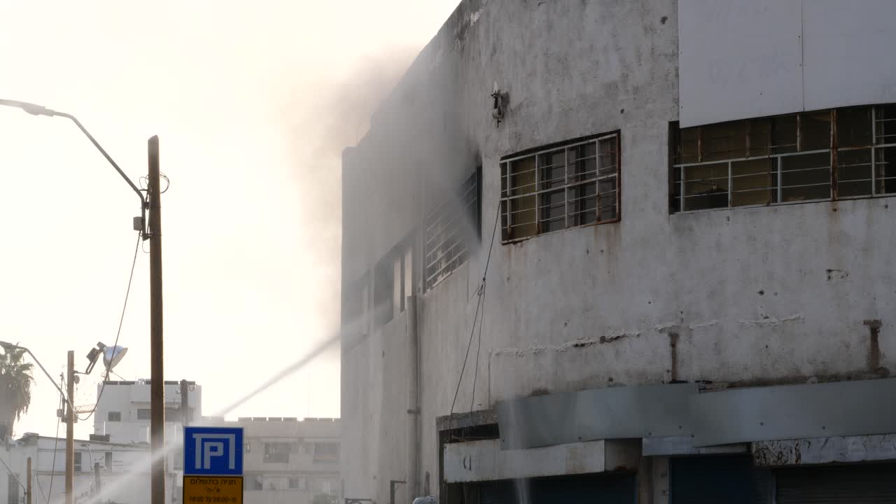 acción de los bomberos, sofocando el fuego en un edificio industrial con chorros de agua