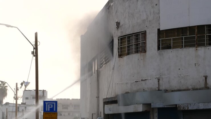 Acción de bomberos, sofocando un incendio en un edificio industrial con chorros de agua