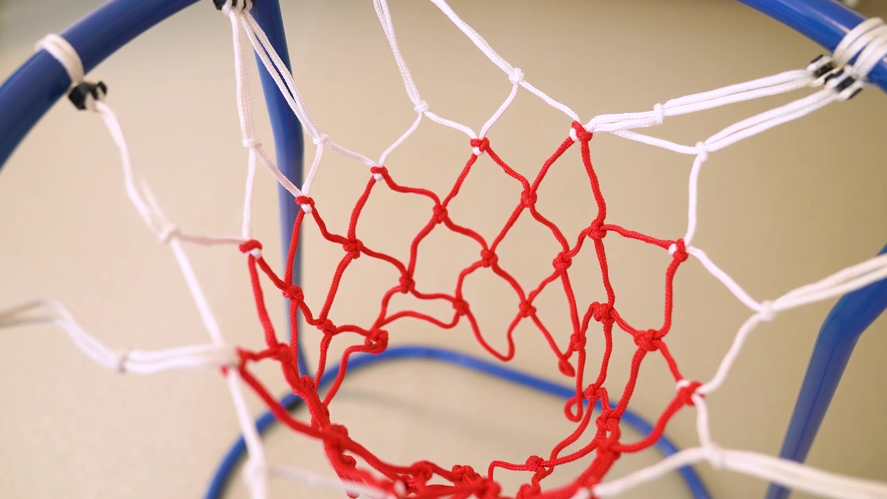 Ring basket biru dan jaring merah putih klasik bergoyang setelah bola melewatinya.