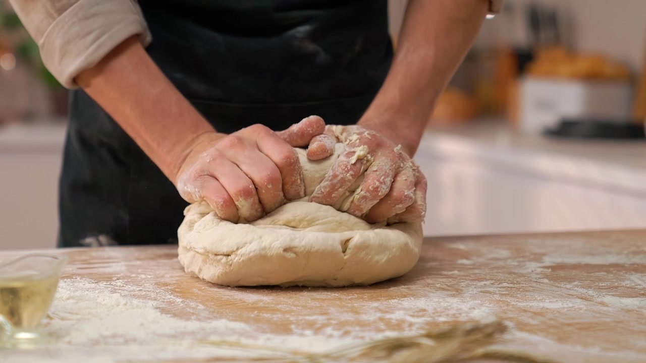 Close-up of Chef's Hands Kneading Fresh Dough on a Floured Wooden Table