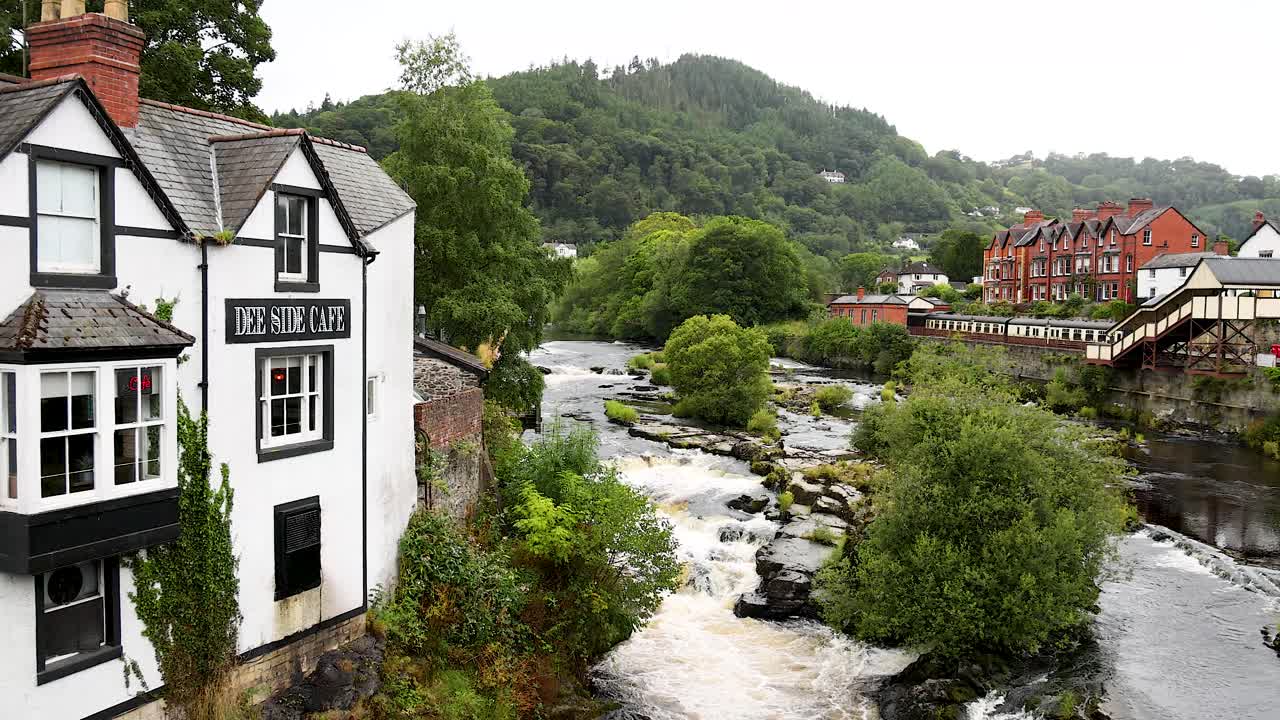 río que fluye más allá de edificios históricos en wrexham, gales