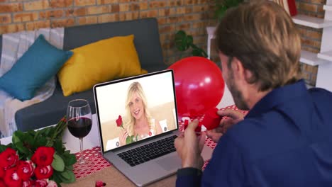 caucasian couple on a valentines date video call man showing ring to smiling woman on laptop screen