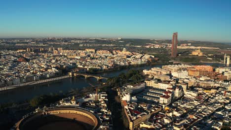 Drone-over-Bullring-of-Real-Maestranza-de-Caballeria-of-Seville-With-Centro-Comercial-TORRE-SEVILLA-In-The-Background-In-Seville,-Spain