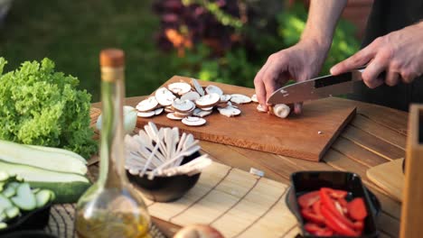 Junger-Mann-Schneidet-Pilze-Auf-Holzbrett-Im-Garten,-Mittlere-Aufnahme