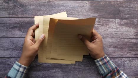 hands holding lined paper on a wooden table