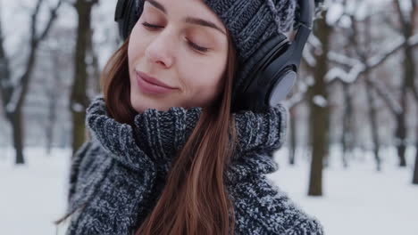 young woman listening to music in a snowy winter park