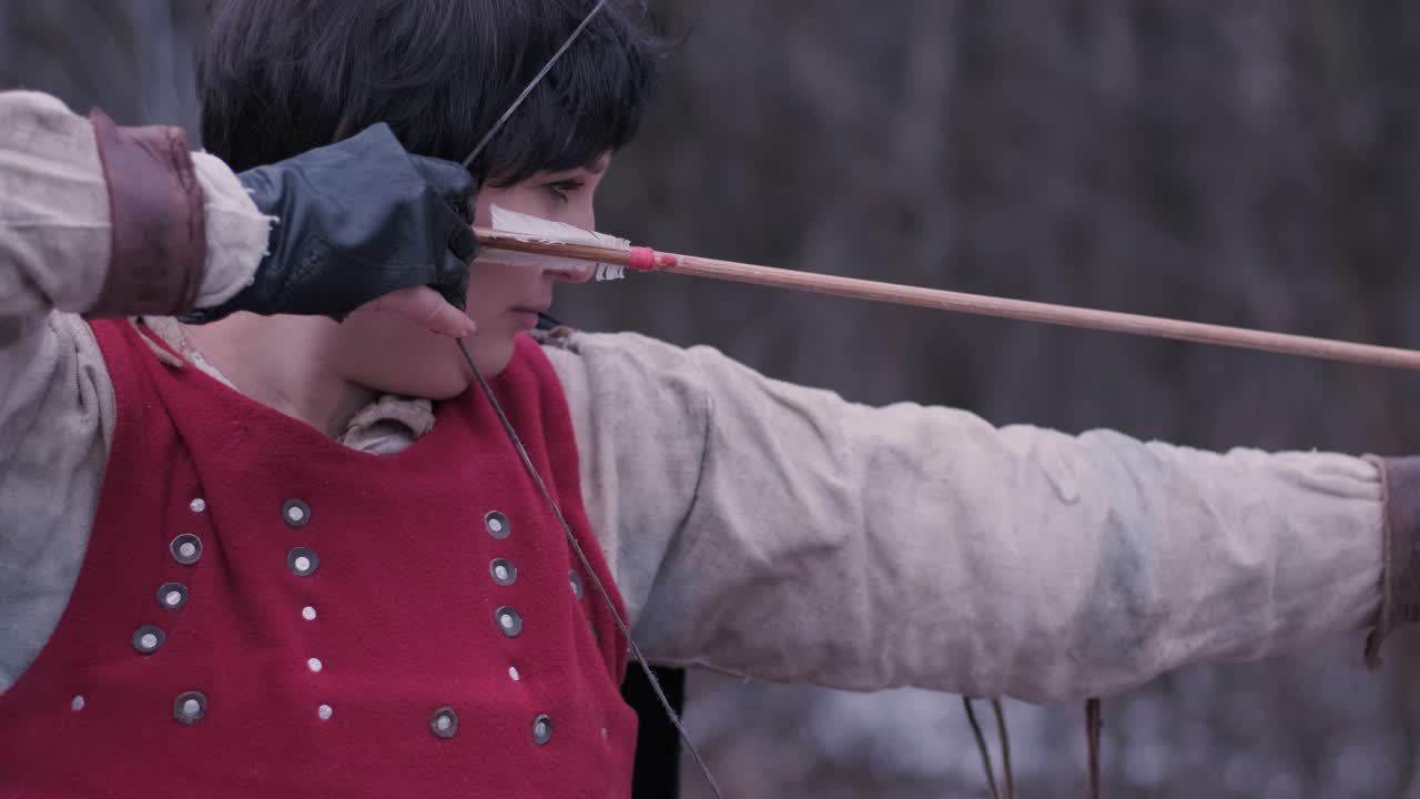 una mujer guerrera dispara un arco en el objetivo.