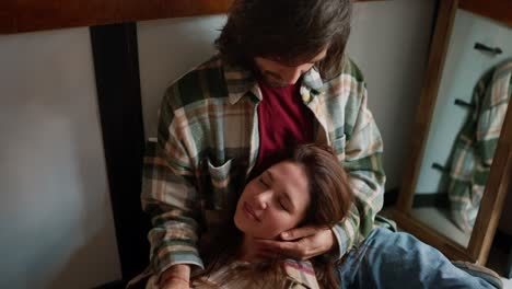 a happy brunette girl in a checkered shirt lies on the lap of her brunette boyfriend in a green checkered shirt, and he strokes her during their communication in a trailer during a picnic outside the city in the summer