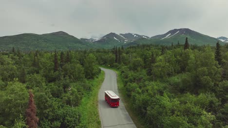 famous trolley red bus isolated in asphalt forest road near downtown anchorage, alaska