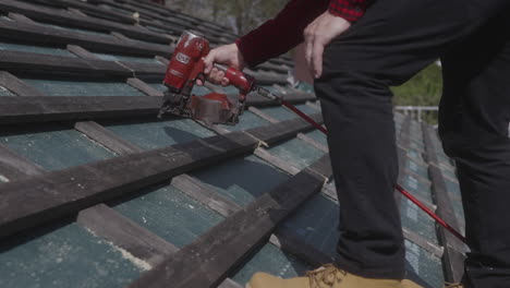 skilled construction worker wearing yellow hard hat no safety gear pneumatic nail gun expertly secure roof tiles moves steadily along roof ensuring tile properly fastened place ensure sturdy secure