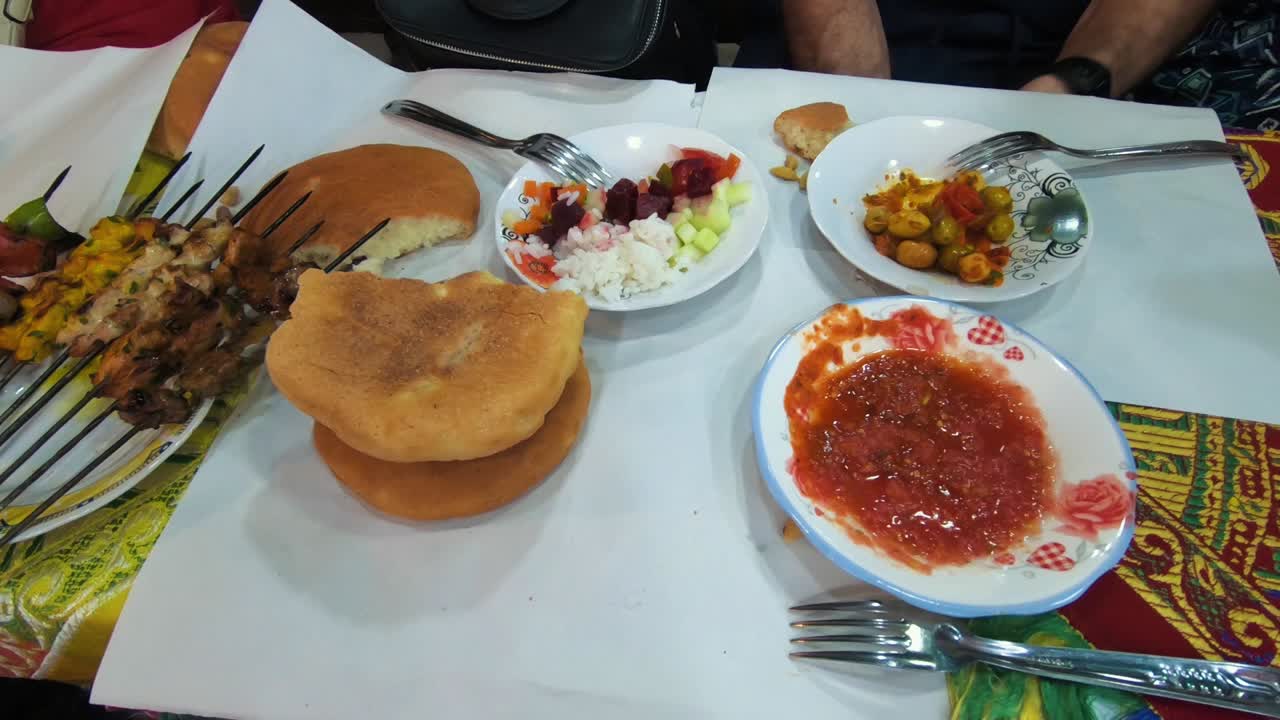 Travelers having street food in the Marrakesh Market. Moroccan bread, kebab, spicy sauce and salad.
