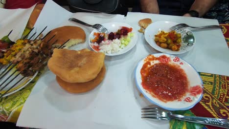 travelers having street food in the marrakesh market. moroccan bread, kebab, spicy sauce and salad.