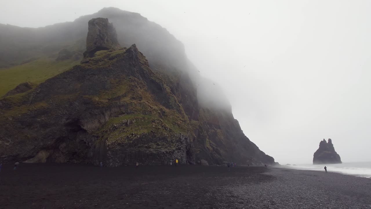 la playa de reynisfjara con pilas de mar en un día de niebla en vik, islandia