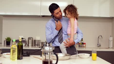 padre sonriente sosteniendo a su hija joven hablando por teléfono
