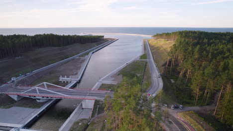 Aerial-trucking-shot-of-Vistula-Spit-Canal-surrounded-by-woodland-and-Baltic-Sea-in-backdrop