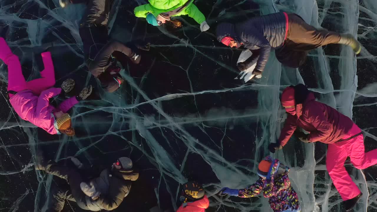 Turistas tumbados sobre el hielo del Lago Baikal congelado realizando movimientos sincronizados