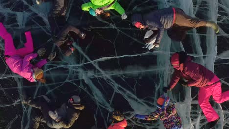 tourists lie on the ice of frozen lake baikal and perform synchronized movements