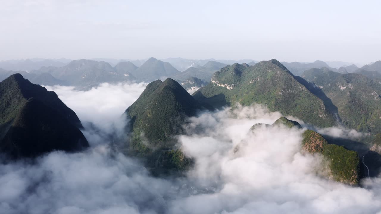Montanhas cársticas asiáticas elevando-se acima de nuvens nebulosas na China remota, em vista aérea