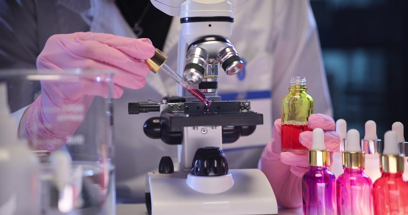 Assistant hand drips serum onto microscope slide in medical lab
