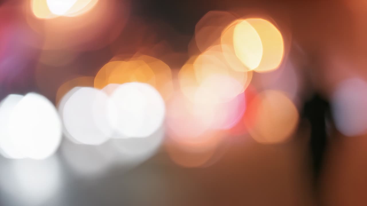 Opening blur showing person silhouette walking along night street, with headlight bokeh, copy space