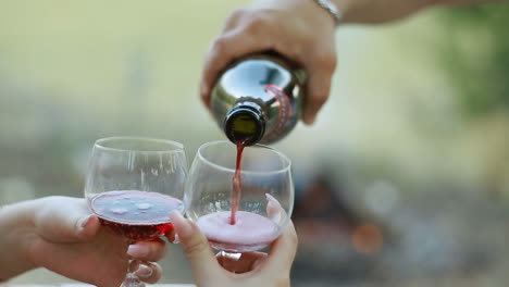 pouring red wine into the glasses. pouring red wine from bottle into the wineglass