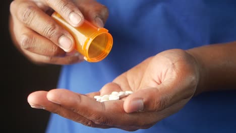la mano de una persona sosteniendo pastillas de una botella