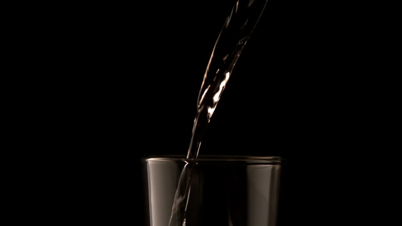 Water pouring into glass on black background