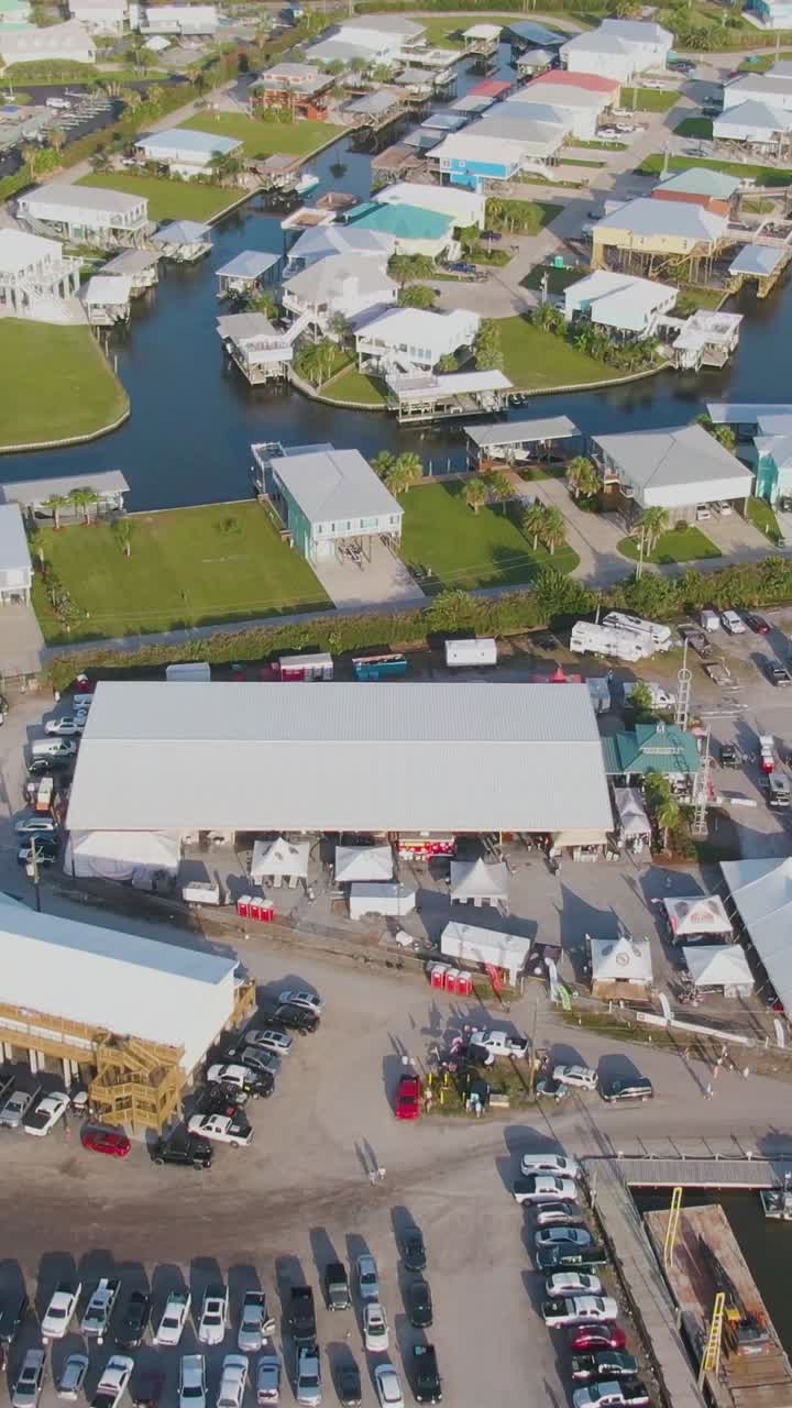 Vertical drone clip showing gated bayou community near a local community center and marina in Grand Isle, Louisiana