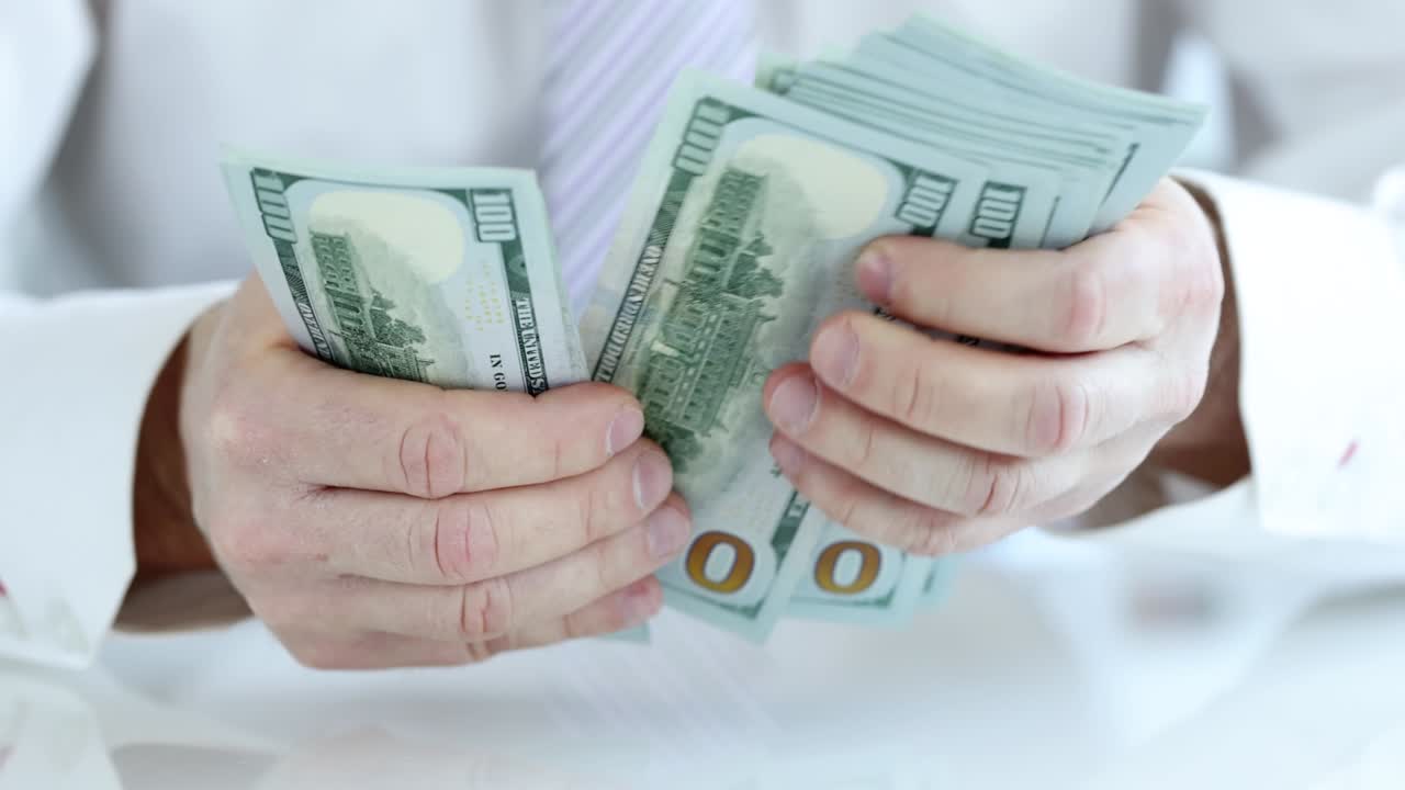 사업가는 현금을 계산합니다. 100달러 미국 지폐.