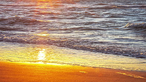 timelapse of sea waves crashing onto the sandy beach at sunset