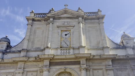 frente de un edificio de la iglesia en una pequeña ciudad en francia hecho de piedra arenisca con un gran reloj, algunas columnas y decoraciones