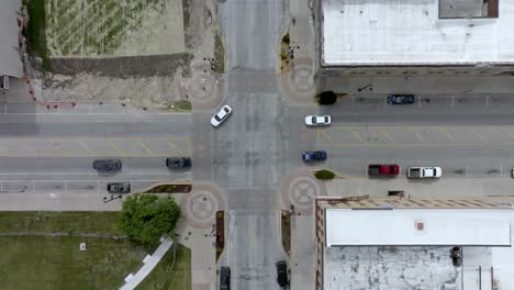 intersection in downtown marshalltown, iowa with traffic moving and drone video overhead moving down