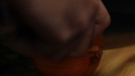 Close-up-slow-motion-shot-as-cutting-the-bottom-of-an-onion,-with-a-big-knife,-processing-vegetables-concept