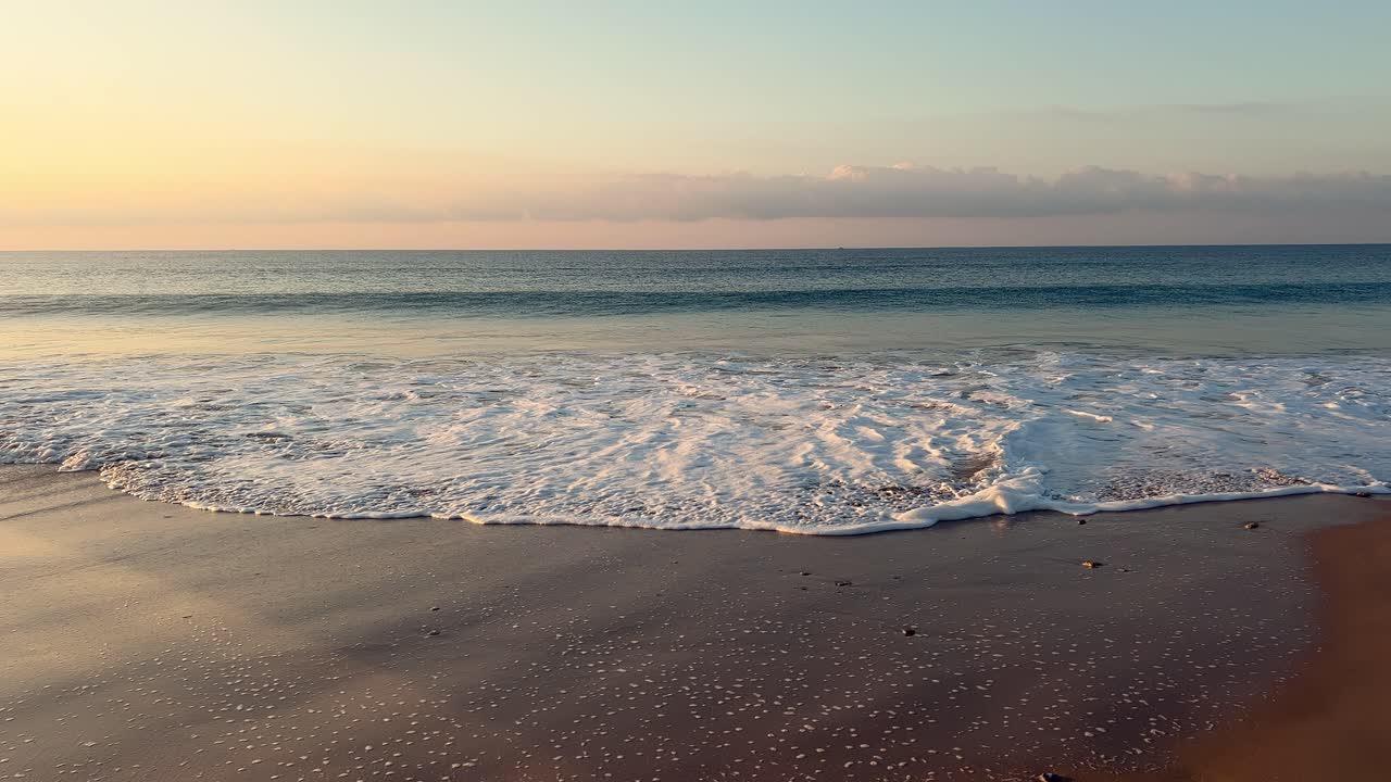 waves lapping on the shore at sunset, slowmo, day