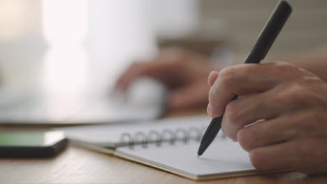 hombre de negocios con pluma escribiendo nuevas citas información en el concepto de organizador raza mixta manos masculinas haciendo notas en papel personal planificador en el escritorio aprender sobre el mercado de valores e inversiones