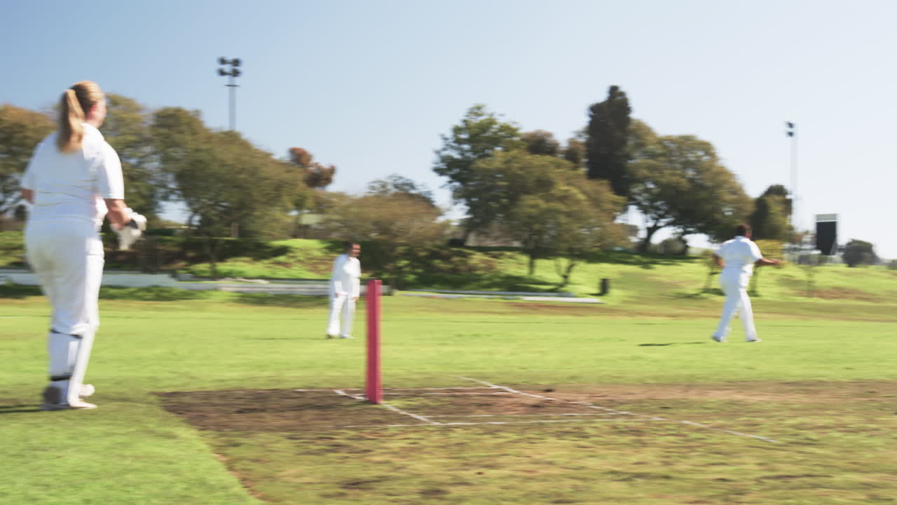 Playing cricket on field, women in white uniforms enjoying outdoor game