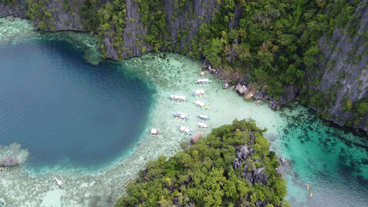 Tour boats and blue hole at twin lagoon amid towering karst and clear water, coron